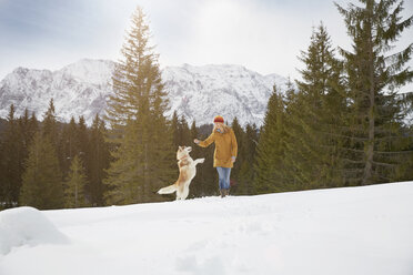 Frau spielt mit Husky in verschneiter Landschaft, Elmau, Bayern, Deutschland - CUF18963