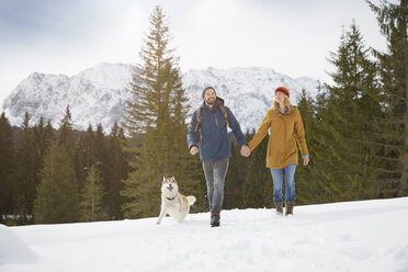 Couple walking husky in snow covered landscape, Elmau, Bavaria, Germany - CUF18964