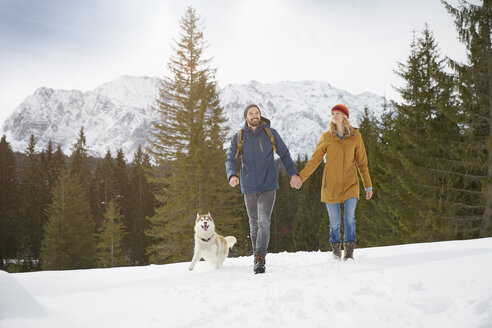 Pärchen mit Husky in verschneiter Landschaft, Elmau, Bayern, Deutschland - CUF18964