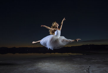 Junge Balletttänzerin springt über Bonneville Salt Flats bei Nacht, Utah, USA - ISF07252