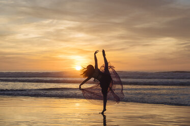 Young female dancer wearing chiffon dress, dancing on beach at sunset, San Diego, California, USA - ISF07260