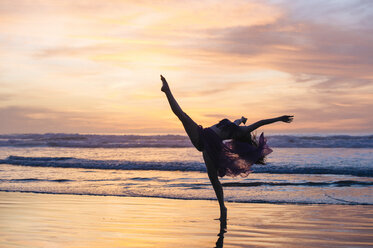 Young female dancer wearing chiffon dress, dancing on beach at sunset, San Diego, California, USA - ISF07262