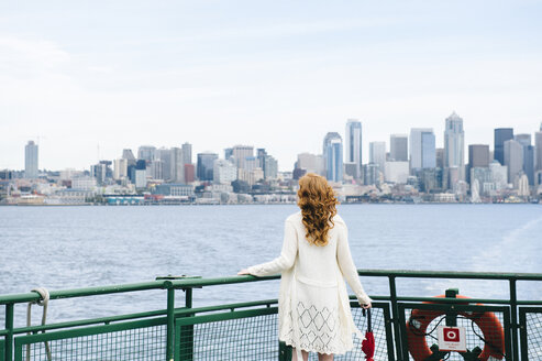 Rückansicht einer Frau mit Blick auf die Skyline der Stadt von einer Passagierfähre auf dem Puget Sound, Seattle, USA - ISF07264