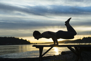 Frau übt Yoga am See bei Sonnenuntergang - ISF07268