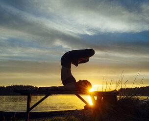 Frau übt Yoga am See bei Sonnenuntergang - ISF07272