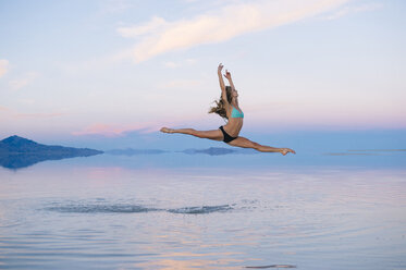 Female ballet dancer jumping mid air over lake, Bonneville Salt Flats, Utah, USA - ISF07283