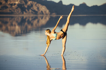 Female ballet dancer poised in ballet position in lake, Bonneville Salt Flats, Utah, USA - ISF07284