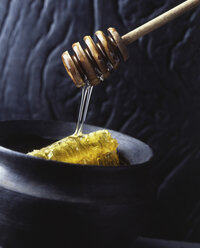 Honey comb in pot with honey dipper dripping honey - ISF07294