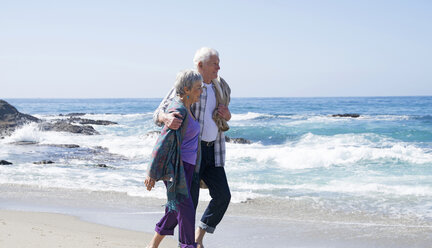 Senior couple walking along beach, smiling - ISF07370
