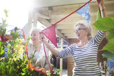 Zwei Frauen im Garten, die bunte Wimpel aufhängen - ISF07389