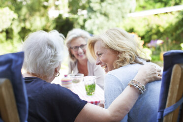 Drei Frauen entspannen sich gemeinsam im Garten und lachen - ISF07392