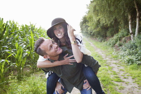 Mid adult man giving girlfriend piggy back in field - ISF07402
