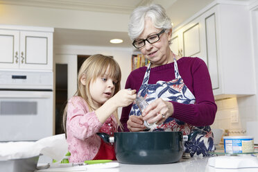 Mädchen und Großmutter messen Salz zum Kochen ab - ISF07425
