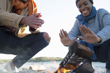 Friends warming hands over camp fire - ISF07430