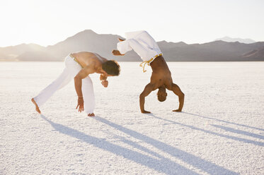 Two men on Bonneville Salt Flats performing capoeira, Utah, USA - CUF19099