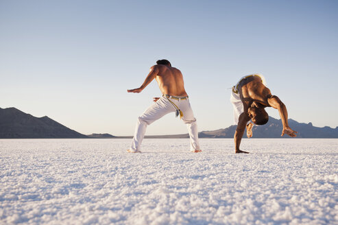 Oberflächenansicht von zwei Männern, die Capoeira auf den Bonneville Salt Flats, Utah, USA, vorführen - CUF19100