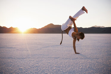 Frau beim Capoeira auf den Bonneville Salt Flats bei Sonnenuntergang, Utah, USA - CUF19102