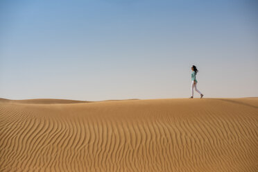 Woman tourist walking on desert dune, Dubai, United Arab Emirates - CUF19136