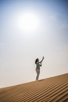 Touristin macht Smartphone-Selfie auf Wüstendüne, Dubai, Vereinigte Arabische Emirate - CUF19137