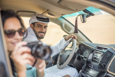 Female tourist in off road vehicle in desert taking photographs, Dubai, United Arab Emirates - CUF19142