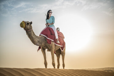 Weibliche Touristin reitet auf einem Kamel in der Wüste, Dubai, Vereinigte Arabische Emirate - CUF19150