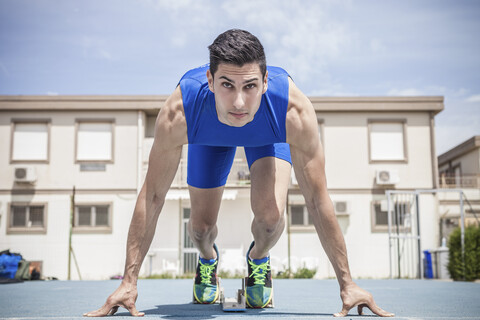 Junger männlicher Sprinter auf der Laufbahn auf seinen Spuren, lizenzfreies Stockfoto