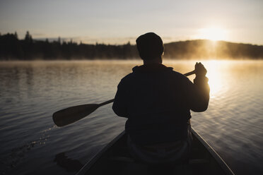 Senior man canoeing on lake at sunset, rear view - CUF19192