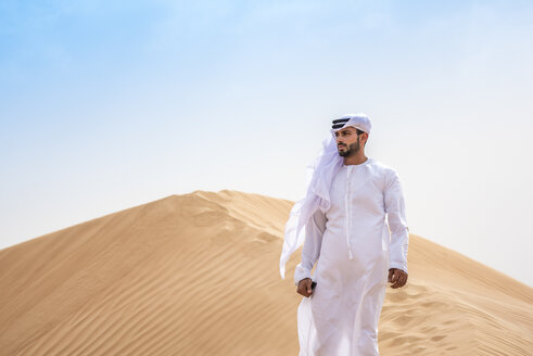 Nahöstlicher Mann in traditioneller Kleidung auf einer Wüstendüne, Dubai, Vereinigte Arabische Emirate - CUF19215