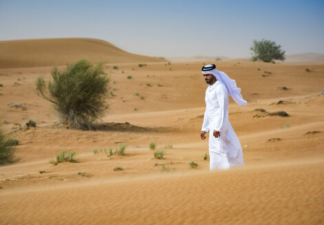 Nahöstlicher Mann in traditioneller Kleidung geht in der Wüste spazieren, Dubai, Vereinigte Arabische Emirate - CUF19219