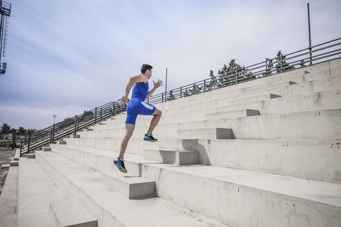 Young male runner running up stairway - CUF19225