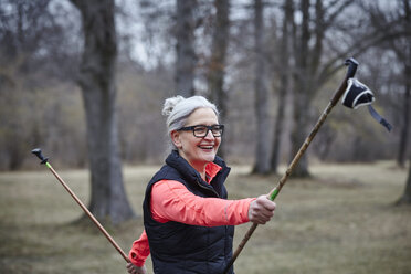 Ältere Frau trainiert im Park, mit Nordic-Walking-Stöcken - CUF19270