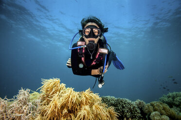 Young woman looking at hard and soft corals whilst scuba diving, Moalboal, Cebu, Philippines - CUF19281