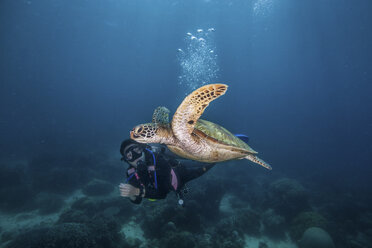 Junge Frau schwimmt mit der seltenen Grünen Meeresschildkröte (Chelonia Mydas), Moalboal, Cebu, Philippinen - CUF19282