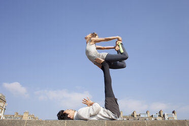 Mann und Frau üben akrobatische Yoga-Balance an der Wand - CUF19330