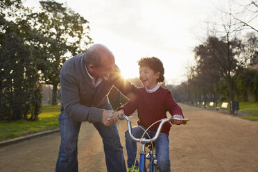 Großvater bringt seinem Enkel im Park das Fahrradfahren bei - CUF19361