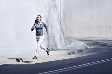 Joggerin mit Kopfhörern auf der Straße - BSZF00433