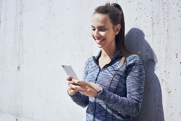 Porträt einer glücklichen Frau, die ihr Smartphone benutzt - BSZF00443