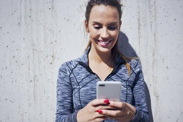 Porträt einer glücklichen Frau, die ihr Smartphone benutzt - BSZF00444