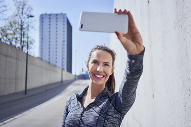 Glückliche Frau nimmt Selfie während städtischen Training - BSZF00445