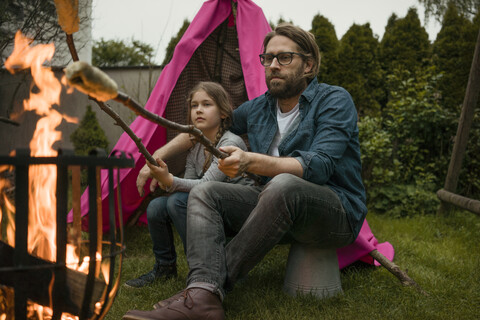 Vater und Tochter grillen Stockbrot über dem Lagerfeuer, lizenzfreies Stockfoto