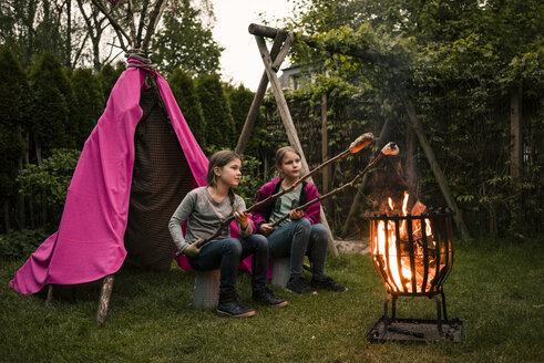 Zwei Mädchen mit Federkopfschmuck, mit Stockbrot am Lagerfeuer - MOEF01211