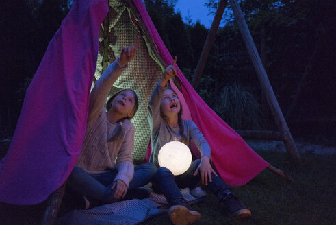 Two girls sitting in tipi, holding lamp as moon - MOEF01221
