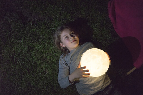 Girl lying on meadow, holding moon stock photo