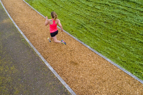 Luftaufnahme einer Joggerin auf dem Holzschnitzelweg, lizenzfreies Stockfoto