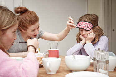 Mid Adult Frau am Frühstückstisch späht unter Töchter Schlafmaske - CUF19529