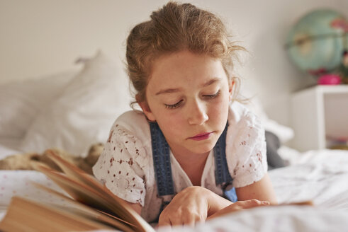 Girl lying on bed reading book - CUF19551