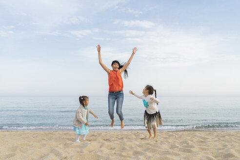 Glückliche Mutter mit zwei am Strand spielenden Töchtern - AFVF00571