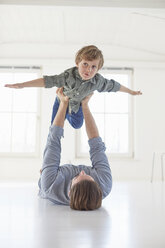 Father lying on floor holding up son - CUF19609