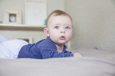 Porträt eines blauäugigen kleinen Jungen auf dem Bett liegend - CUF19726