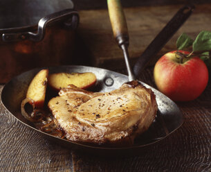 Schweinekotelett mit Apfel und Zwiebeln in einer klassischen Pfanne gebraten - CUF19753